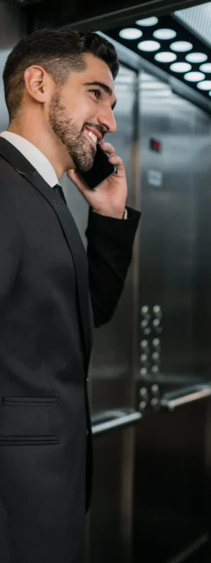 portrait-young-businessman-talking-phone-hotel-elevator-business-travel-concept