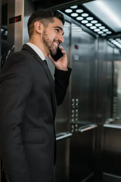 portrait-young-businessman-talking-phone-hotel-elevator-business-travel-concept
